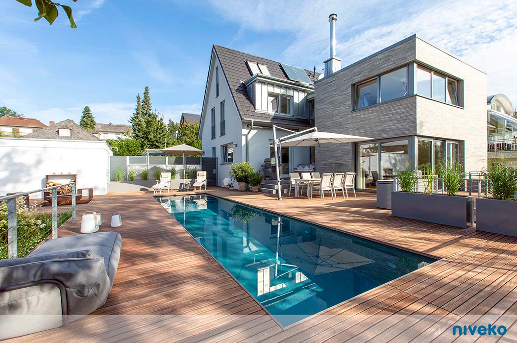 Modernes Haus mit grossem Pool und Holzterrasse an einem sonnigen Tag