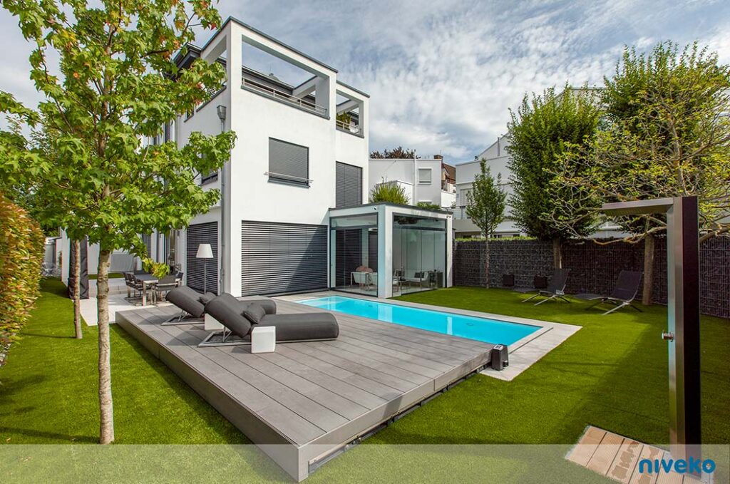 Modern weißes Haus mit Pool, grünen Rasenflächen und stilvollen Sonnenliegen