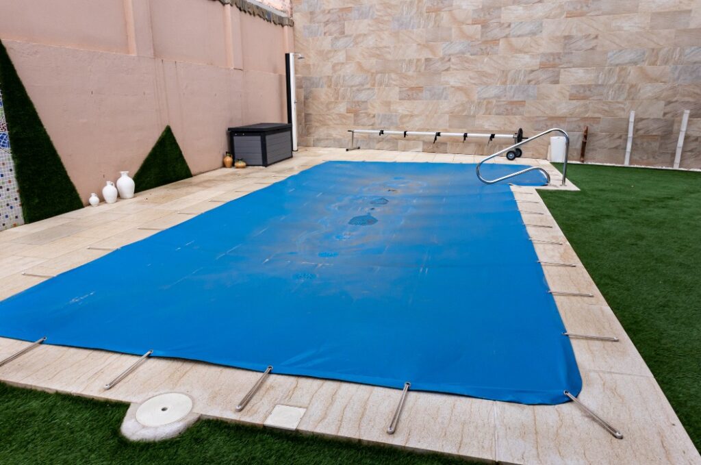Ein kleiner Pool, der während der Wintersaison mit einer blauen Plane abgedeckt wird, um ihn zu schützen und Verschmutzungen zu vermeiden.