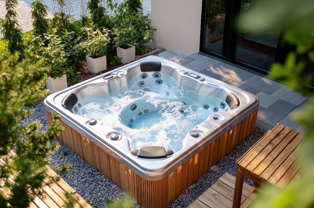 Ein moderner Whirlpool, eingebettet in eine landschaftlich gestaltete Außenterrasse.