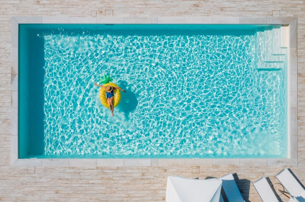 Eine attraktive junge Frau im Bikini, mit Strohhut und Sonnenbrille