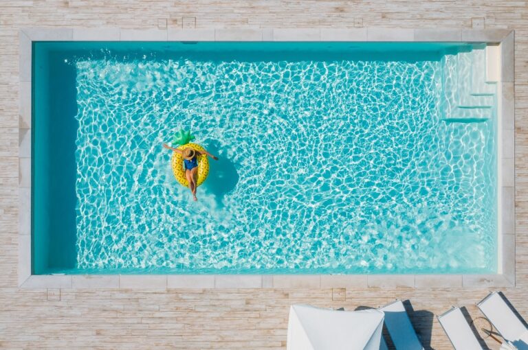 Eine attraktive junge Frau im Bikini, mit Strohhut und Sonnenbrille