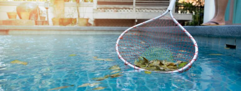 Eine Frau, die mit einem Netz Laub aus dem Schwimmbecken entfernt