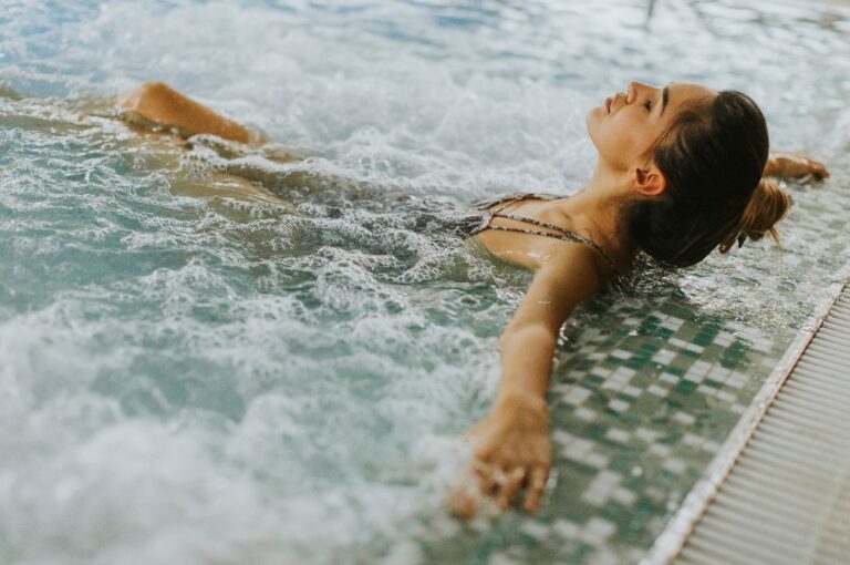 Eine junge Frau entspannt sich in der Whirlpool-Badewanne am Pool