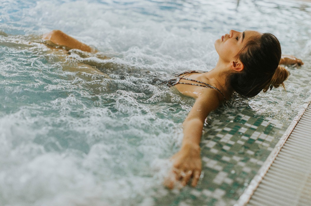 Eine junge Frau entspannt sich in der Whirlpool-Badewanne am Pool