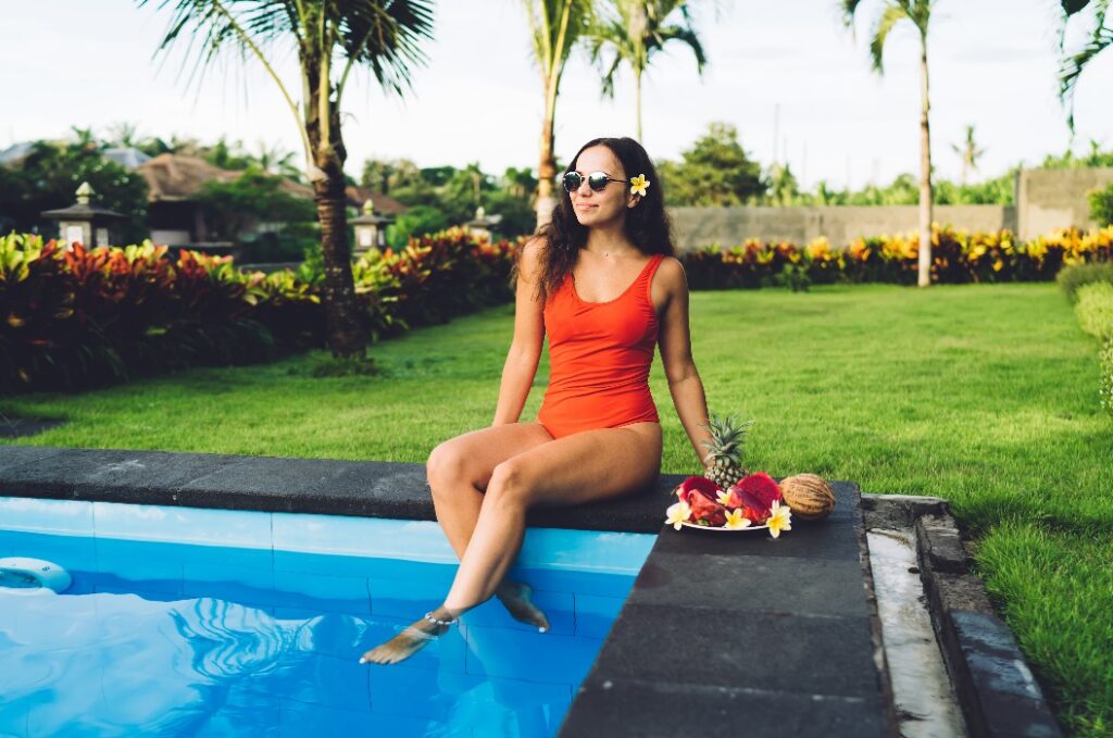 Eine schlanke Frau mit Sonnenbrille, die sich am Swimmingpool ausruht