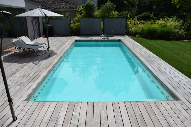 Ein leerer Swimmingpool mit klarem türkisfarbenem Wasser und zwei weißen Liegen