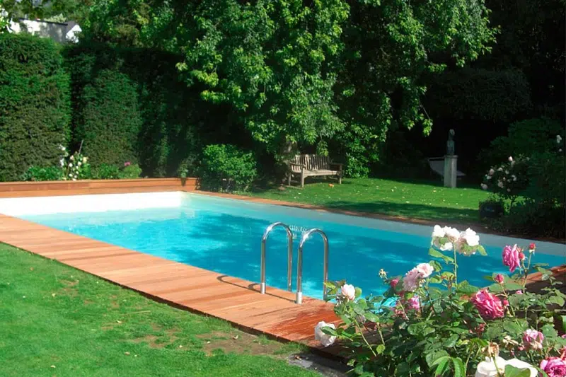 Ein leerer Swimmingpool mit klarem Wasser, umgeben von grünem Rasen und Rosen