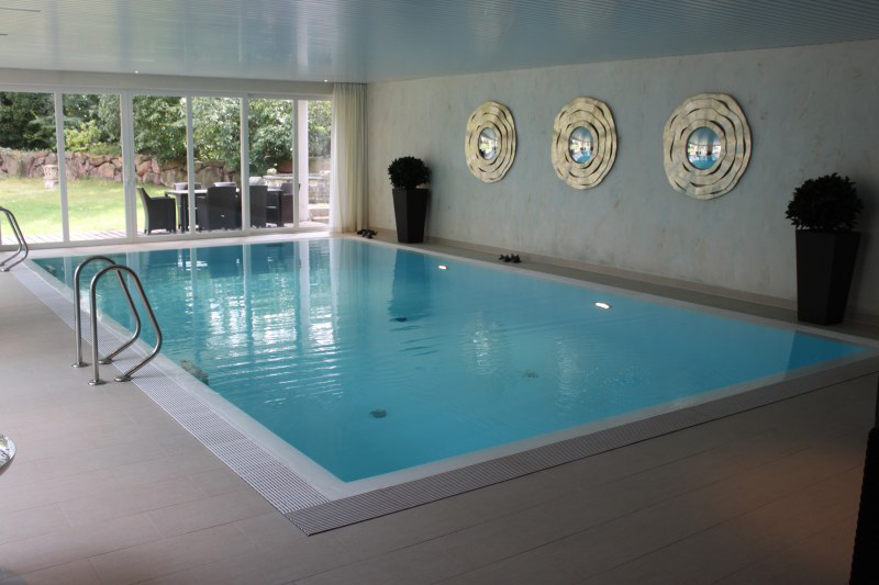 Heller Innenpool mit klarem Wasser, Wanddeko in Gold und großen Fenstern