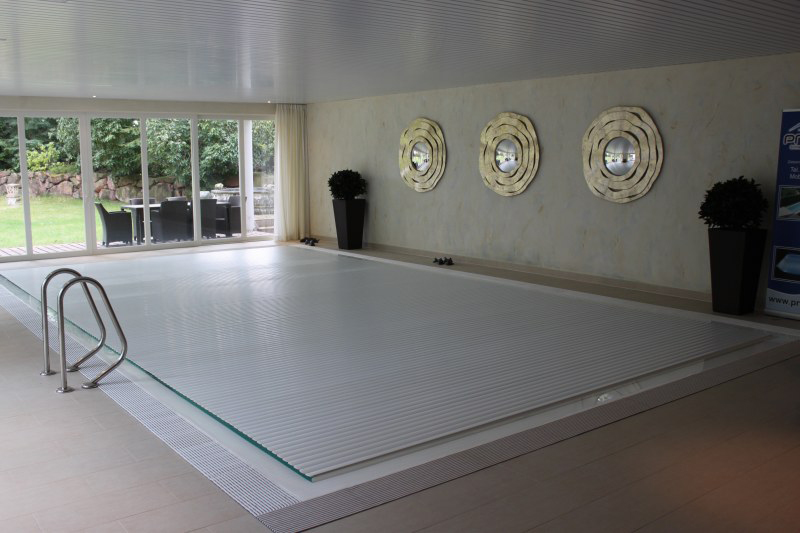 Ein heller Innenpool mit geschlossener Abdeckung, hellen Wänden und goldenen Wanddekoren