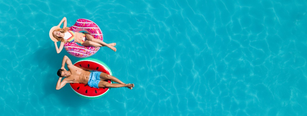 Glückliches Paar mit Schwimmreifen im Swimmingpool, Ansicht von oben