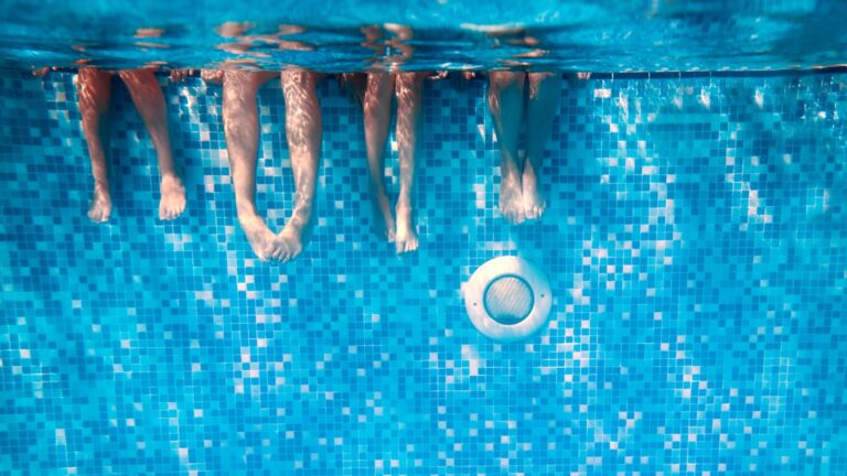 Kinder und Erwachsene mit den Beinen im Wasser im Schwimmbad