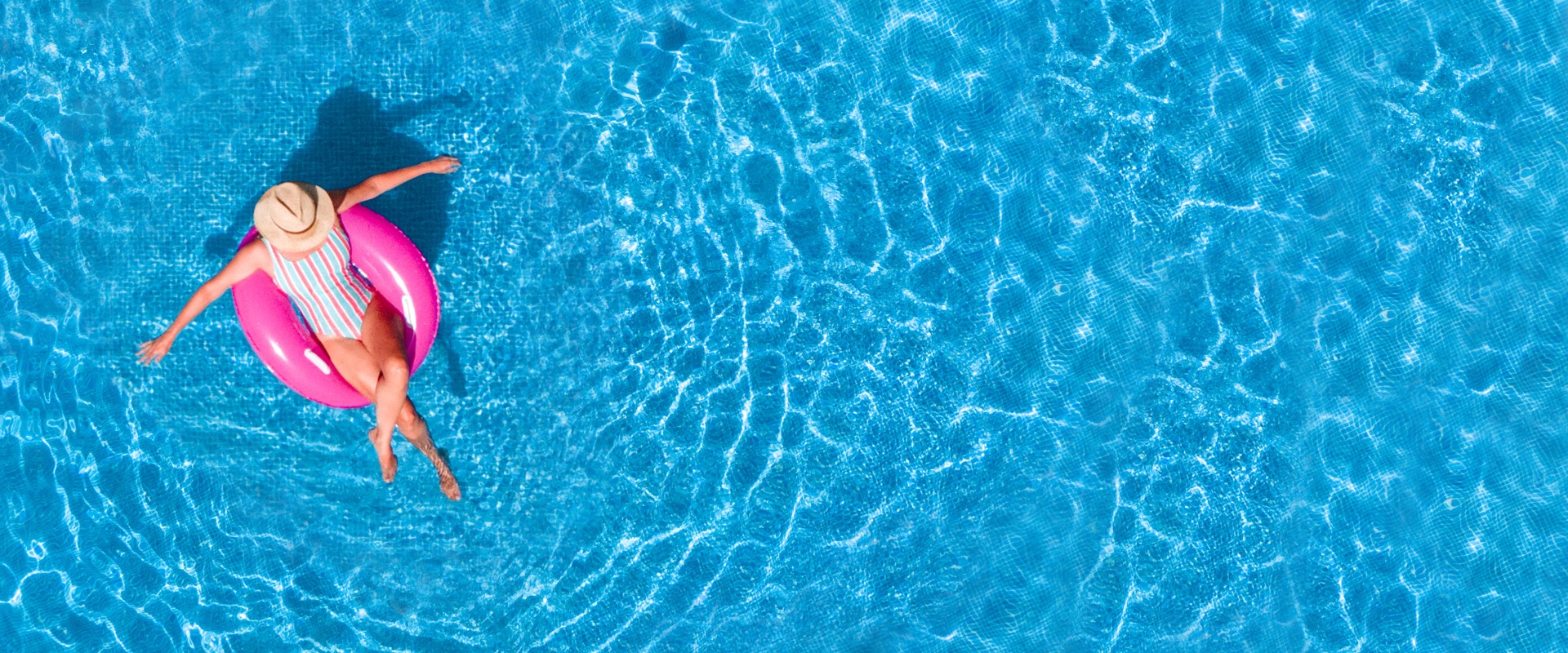 Luftaufnahme eines Schwimmbads im Sommer aus der Vogelperspektive. Ein junges Mädchen in einem