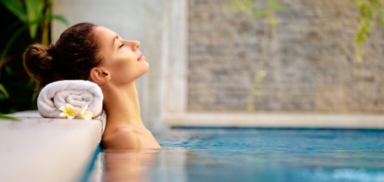 Schönheits- und Körperpflege. Sinnliche junge Frau, die sich im Außenpool eines Wellnessbereichs entspannt.