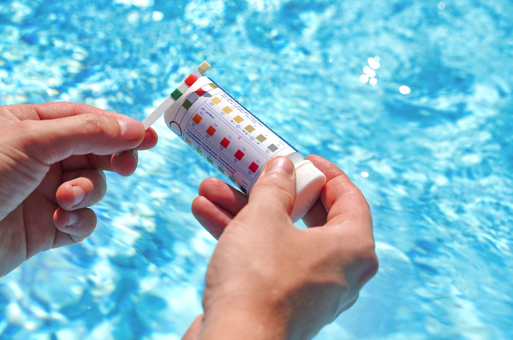 Überprüfung der Wasserqualität eines Schwimmbeckens mithilfe eines Teststreifens für pH-Wert, Chlor und Algenbekämpfungsmittel