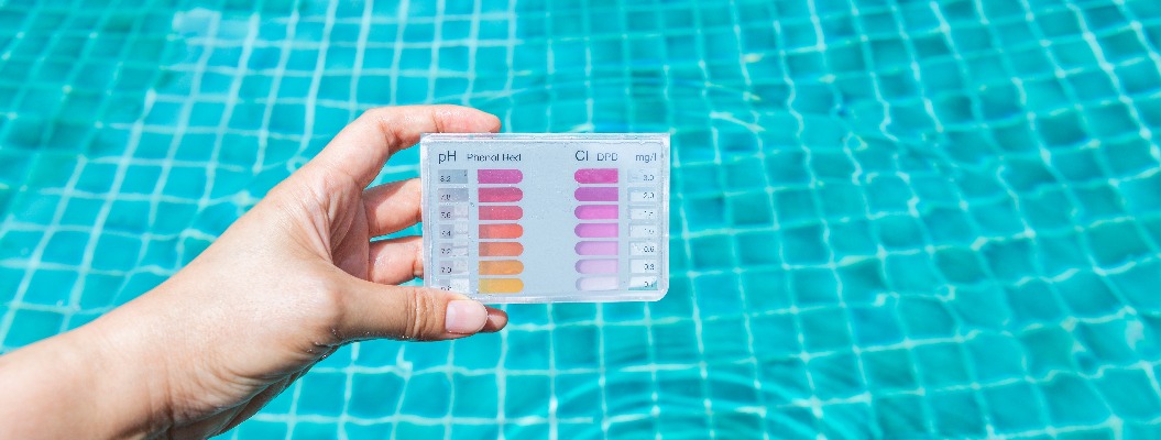 Wassertest-Set in der Hand eines Mädchens vor einem verschwommenen, sauberen und klaren Schwimmbadwasser, Wasseranalysegeräte für Schwimmbadwasser, Sommer im Freien bei Tageslicht