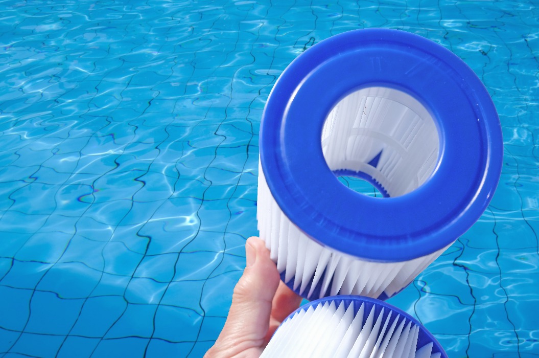 Wiederverwendbare Pool-Patronenfilter liegen vor dem Hintergrund von Poolwasser in einer menschlichen Hand. Reinigung und Wartung, Austausch des Wasserfilters.