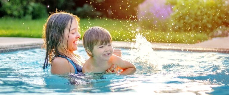 Happy siblings playing in swimming pool outdoors in garden. Pret