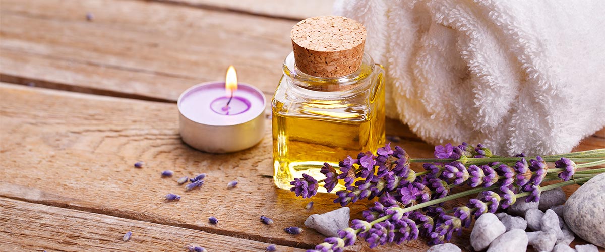 Lavendel neben einem Handtuch, Aromaöl und Duftkerze in einer Sauna.