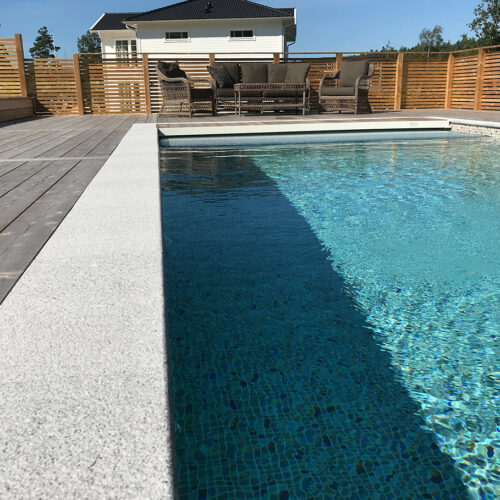 Ein moderner Pool mit klarem Wasser und Terrassenumrandung in einem Hinterhof