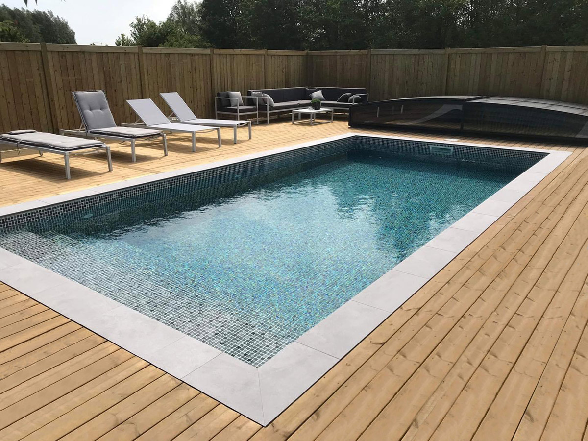 Ein moderner Pool mit Holzdeck, Liegestühlen und Sitzbereich im Freien.
