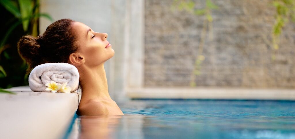 Schönheit und Körperpflege. Sinnliche junge Frau, die sich im Outdoor-Spa-Swimmingpool entspannt.