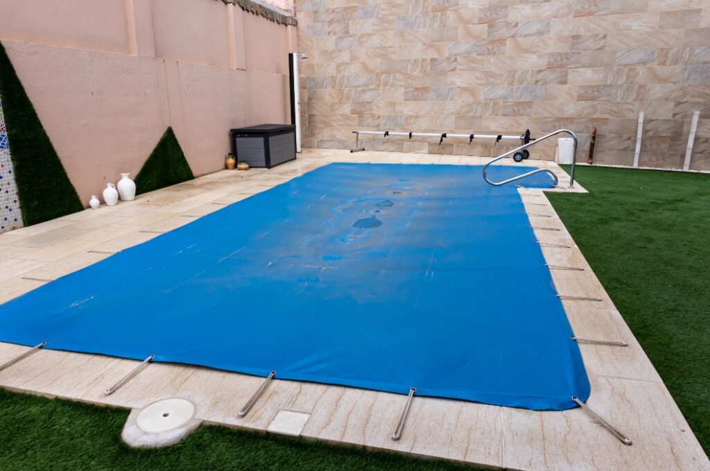 Kleiner Pool, der in der Wintersaison mit einer blauen Plane abgedeckt ist, um ihn vor Verschmutzung zu schützen.